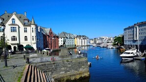 A canal with buildings on either side, a stone bridge, and boats docked along the water. - Cozy Ålesund Apartment With Private Entrance & Free Parking (Ålesund)
