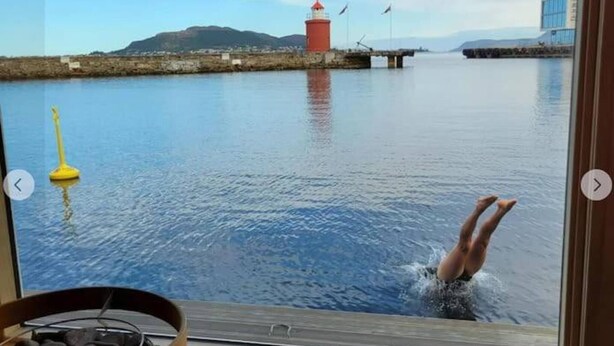 A view from a window overlooking a calm body of water with a lighthouse and mountains in the distance. - Cozy Ålesund Apartment With Private Entrance & Free Parking (Ålesund)