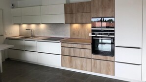 Una cocina moderna con armarios blancos, una pared de acento de madera y electrodomésticos integrados.