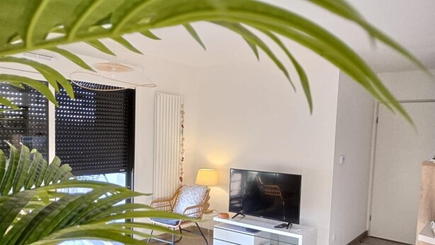 Una sala de estar moderna con televisor, sofá, mesa de centro y planta en maceta.