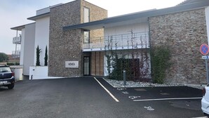 Un edificio moderno con fachada de piedra, un letrero que dice "HENEA" y un área de estacionamiento con espacios para discapacitados.