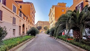A street lined with yellow buildings, some with balconies and greenery. - Domus Augustea San Giovanni Sunset Suites (Rome)