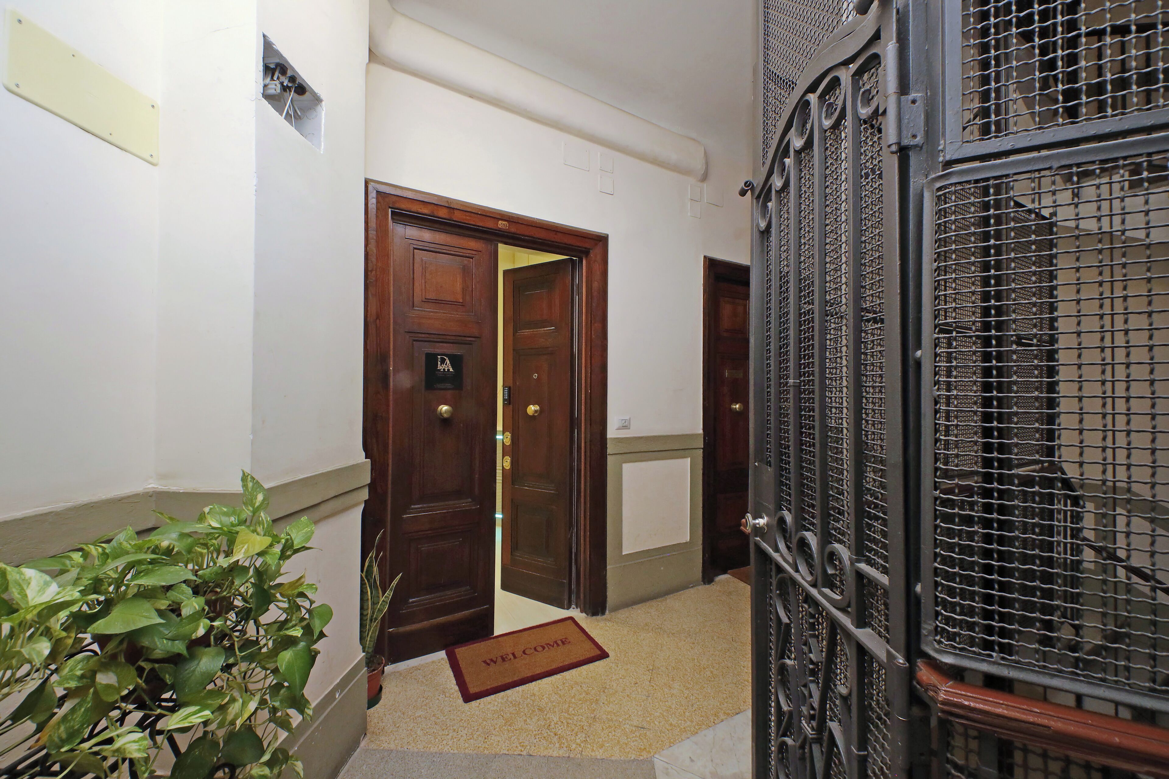 A hallway with a wooden door, a metal gate, and a welcome mat.