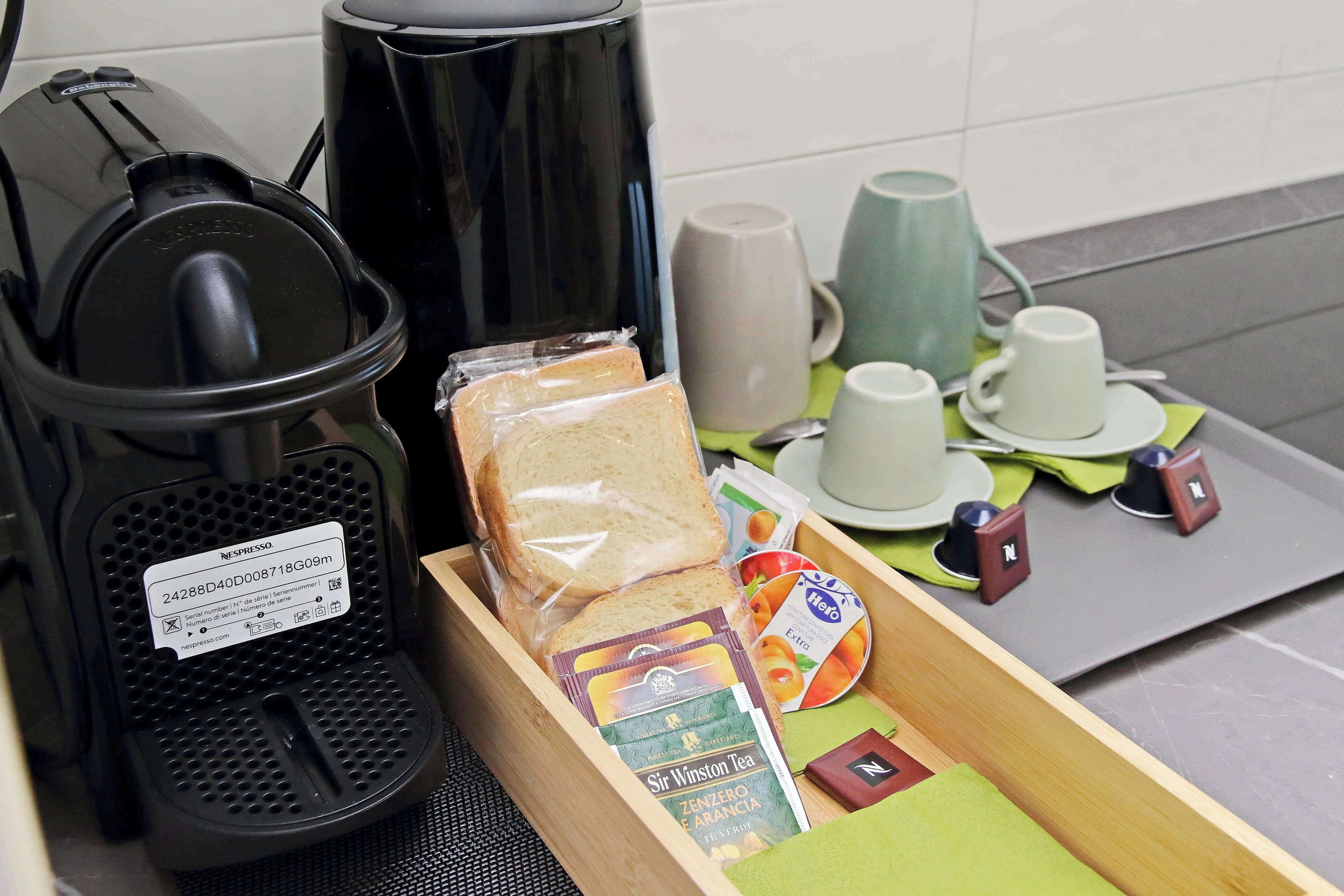 Une machine à café, un plateau avec du pain, des sachets de thé et des tasses.