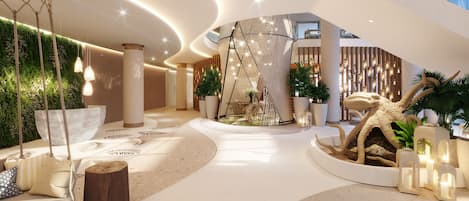 A modern lobby with a central seating area, a decorative sculpture, and a variety of plants.