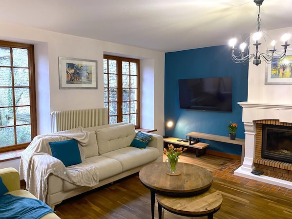 A living room with a sofa, a coffee table, a fireplace, and a TV mounted on the wall.