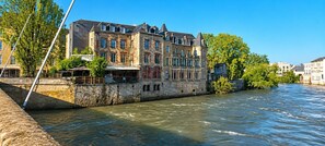Een historisch gebouw met meerdere verdiepingen, een stenen gevel en een rivier op de voorgrond.