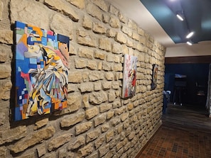 A hallway with a stone wall and three colorful paintings.