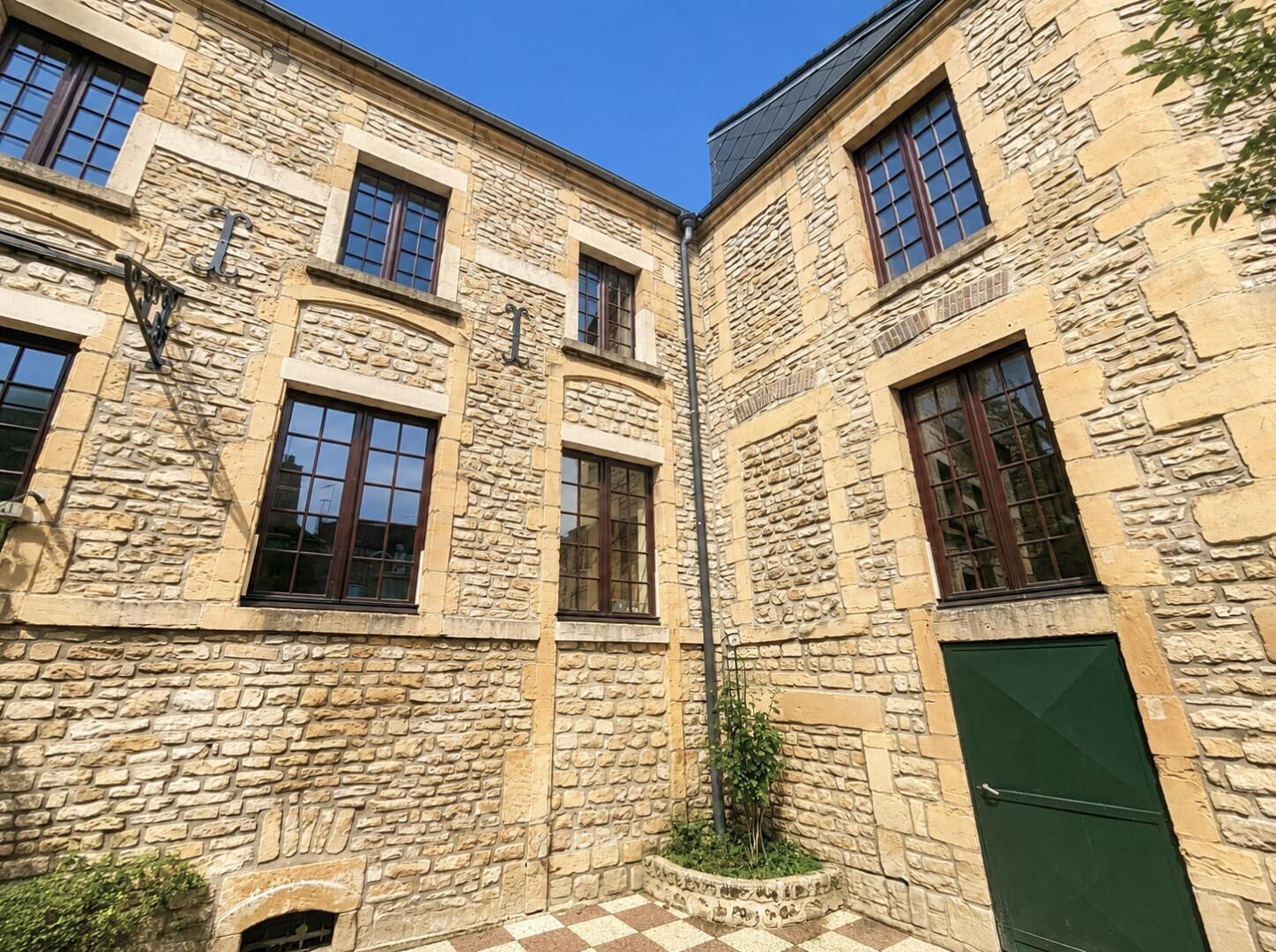 A stone building with multiple windows and a green door.