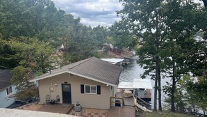 A house with a small porch, a covered dock, and a view of a lake. - Your Lake Escape Awaits! – 3BR/2BA with Private Dock in a Fun Cove at 2MM (Lake Ozark)