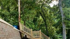 A wooden staircase leading up a sloped, gravel-covered area with a brick wall on one side and a concrete path on the other. - Your Lake Escape Awaits! – 3BR/2BA with Private Dock in a Fun Cove at 2MM (Lake Ozark)