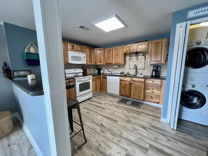 A compact kitchen with wooden cabinets, a microwave, an oven, a dishwasher, and a washing machine.