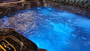 A hot tub with a leaf-patterned wall and string lights. - The Ardmore Executive Suite (Winston-Salem)