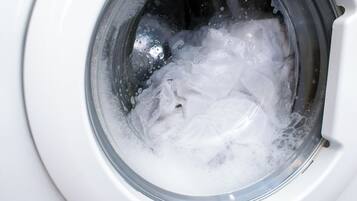 A washing machine in operation with water and foam inside.