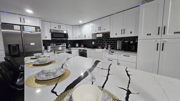 A modern kitchen with white cabinets, stainless steel appliances, and a marble countertop. - The Ardmore Executive Suite (Winston-Salem)