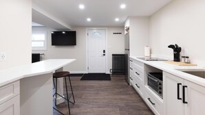 Une cuisine moderne avec des meubles blancs, un plan de travail noir et un four encastré.