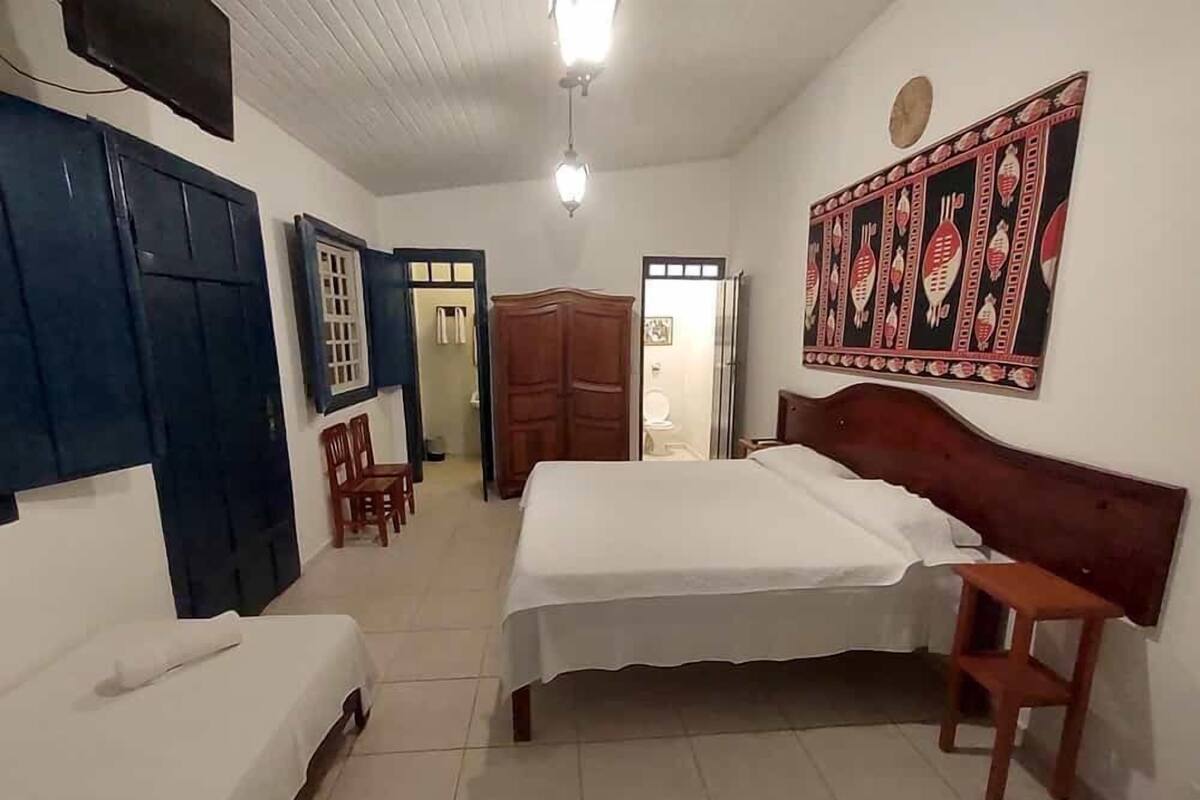 Un dormitorio con dos camas, un armario, una silla y una pared con diseño decorativo.