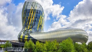 Um edifício de arquitetura moderna com um design curvo e original, rodeado por vegetação exuberante.