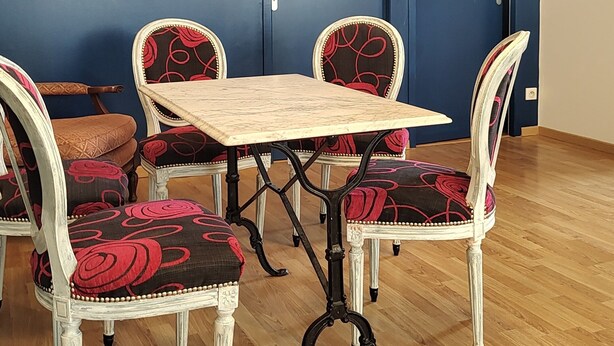 Uma sala de jantar com mesa e cadeiras de madeira, parede azul e chão de madeira.
