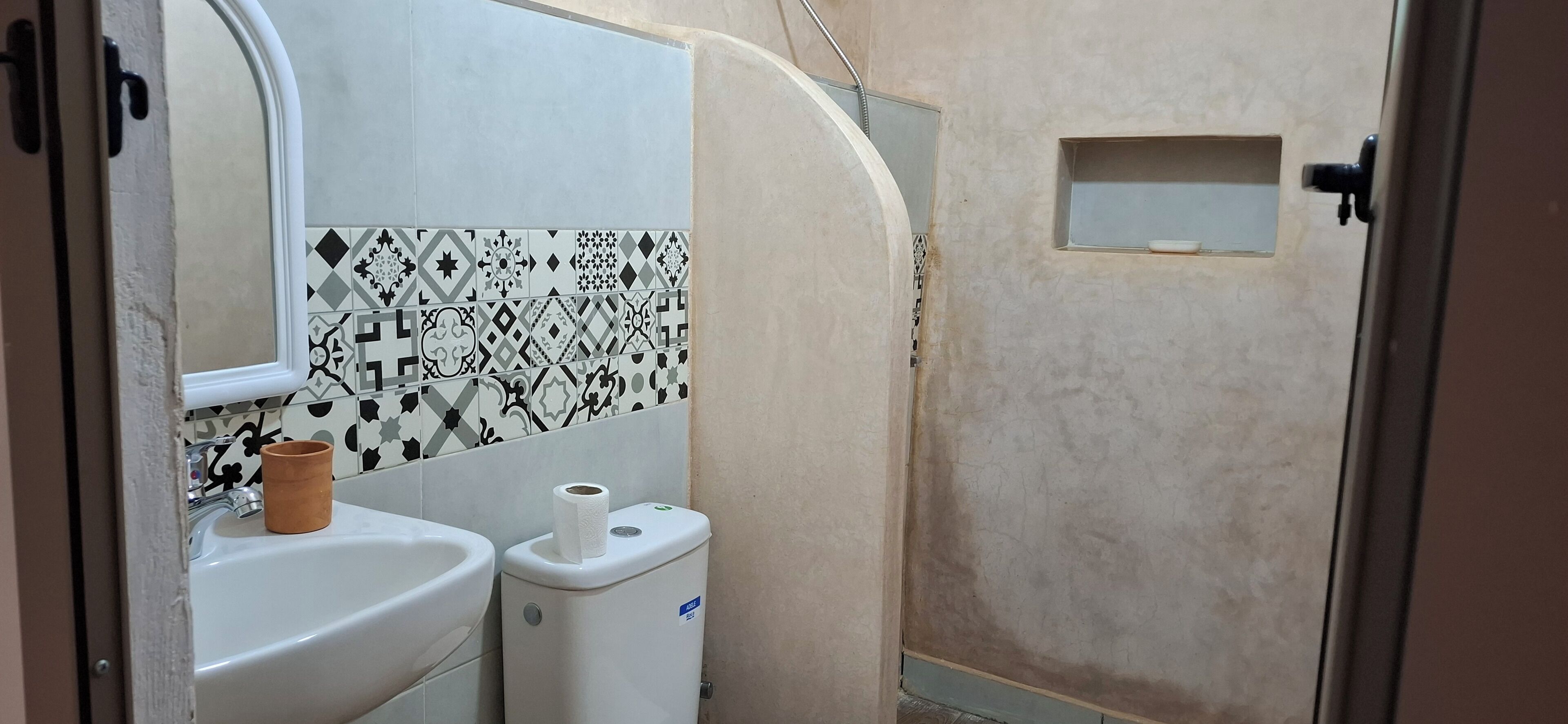 A bathroom with a sink, toilet, and a small window.