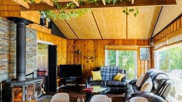 L’intérieur chaleureux d’un chalet avec une cheminée en pierre, un canapé et une table à manger dressée pour le repas.