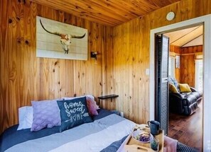 Relax in this inviting cabin room featuring a plush bed, wooden wall art, and a cozy reading nook.