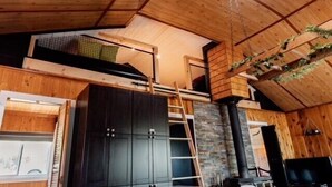 Un intérieur en bois avec une mezzanine, une cheminée et un escalier menant à l’étage supérieur.