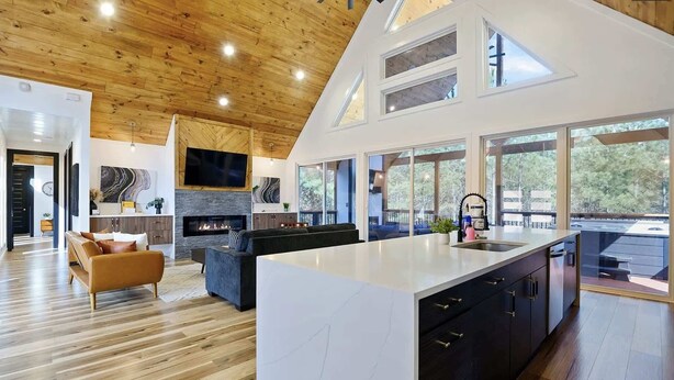 A modern kitchen with a large island, a built-in fireplace, and a dining area with a view of the outdoors. - Couples - Family - Games - Hot tub - Sauna (Broken Bow)
