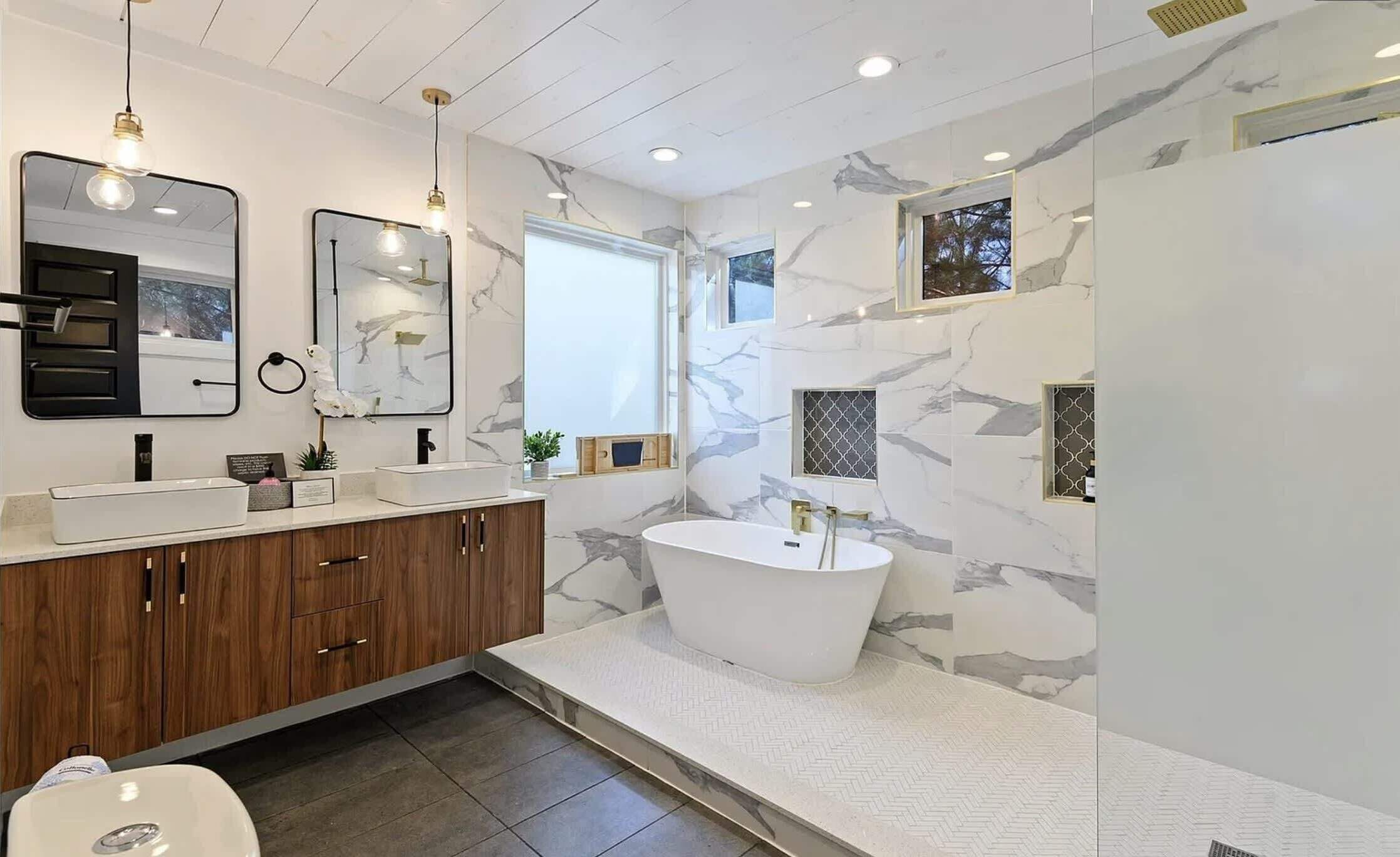 A modern bathroom with a freestanding bathtub, a vanity with a double sink, and a large mirror.