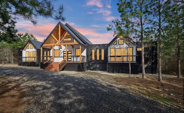 Eine moderne Holzhütte mit einer zentralen Holztreppe, großen Fenstern und einem symmetrischen Design.
