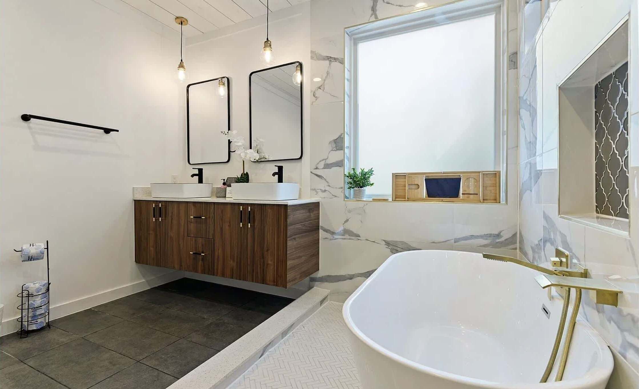 A modern bathroom with a freestanding bathtub, double sinks, and a large mirror.