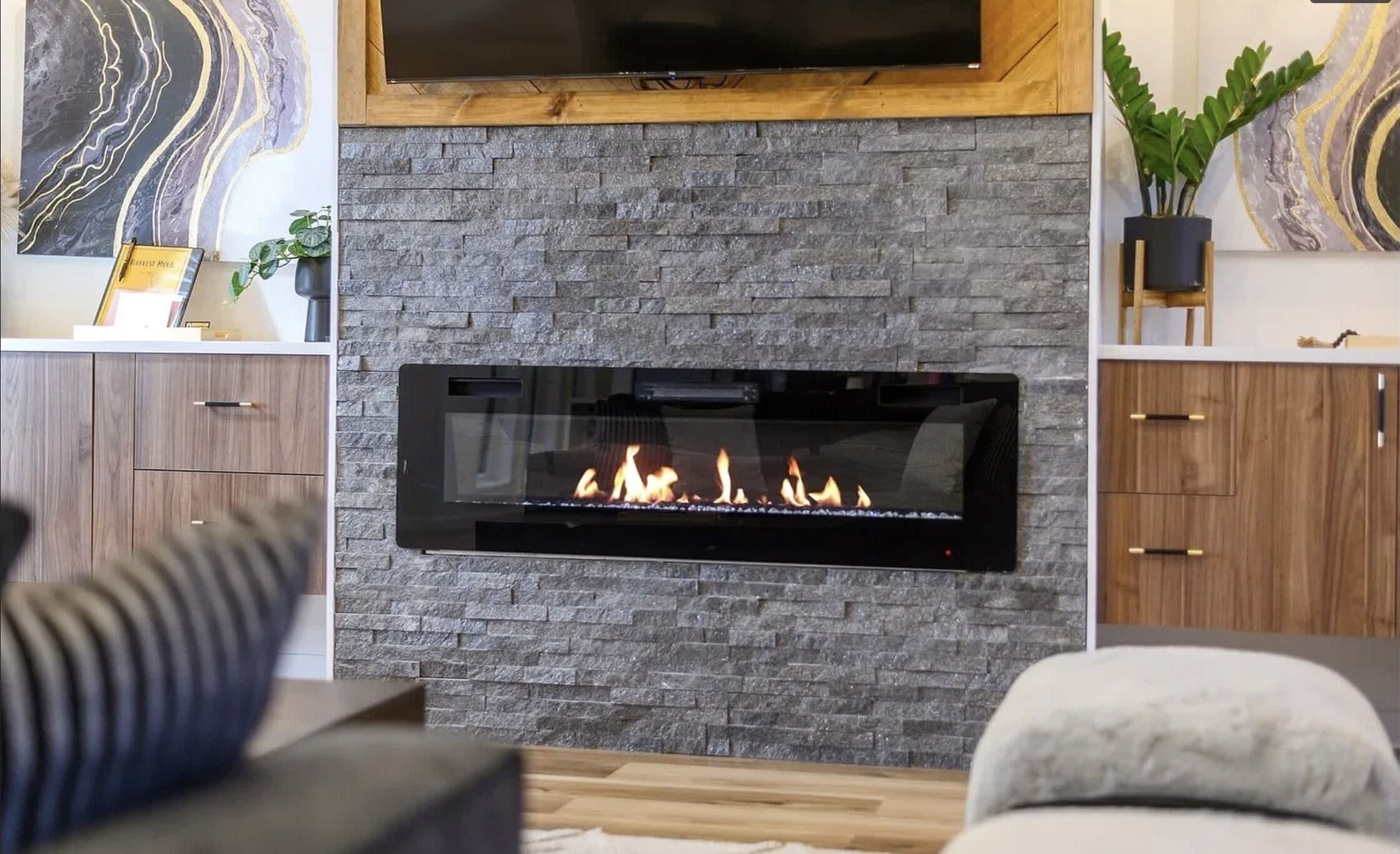 A modern living room with a stone fireplace, wooden cabinets, and a flat-screen TV mounted above the fireplace.