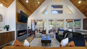 A spacious living area with a fireplace, a large TV mounted on the wall, and a cozy seating arrangement. - Couples - Family - Games - Hot tub - Sauna (Broken Bow)
