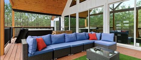 An outdoor living area with a sectional sofa, a glass-top coffee table, and a wooden deck.