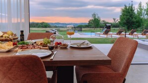 Een eettafel gedekt met eten en drinken, met uitzicht op een zwembad en een terras.