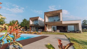 Een modern herenhuis met zwembad, terras en een verzorgd gazon.