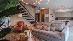 Een moderne woonkamer met een gestreept bankje, een houten stoel en een trap.
