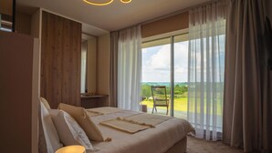 Een slaapkamer met een groot bed, een nachtkastje, een stoel en uitzicht op een balkon met een stoel.