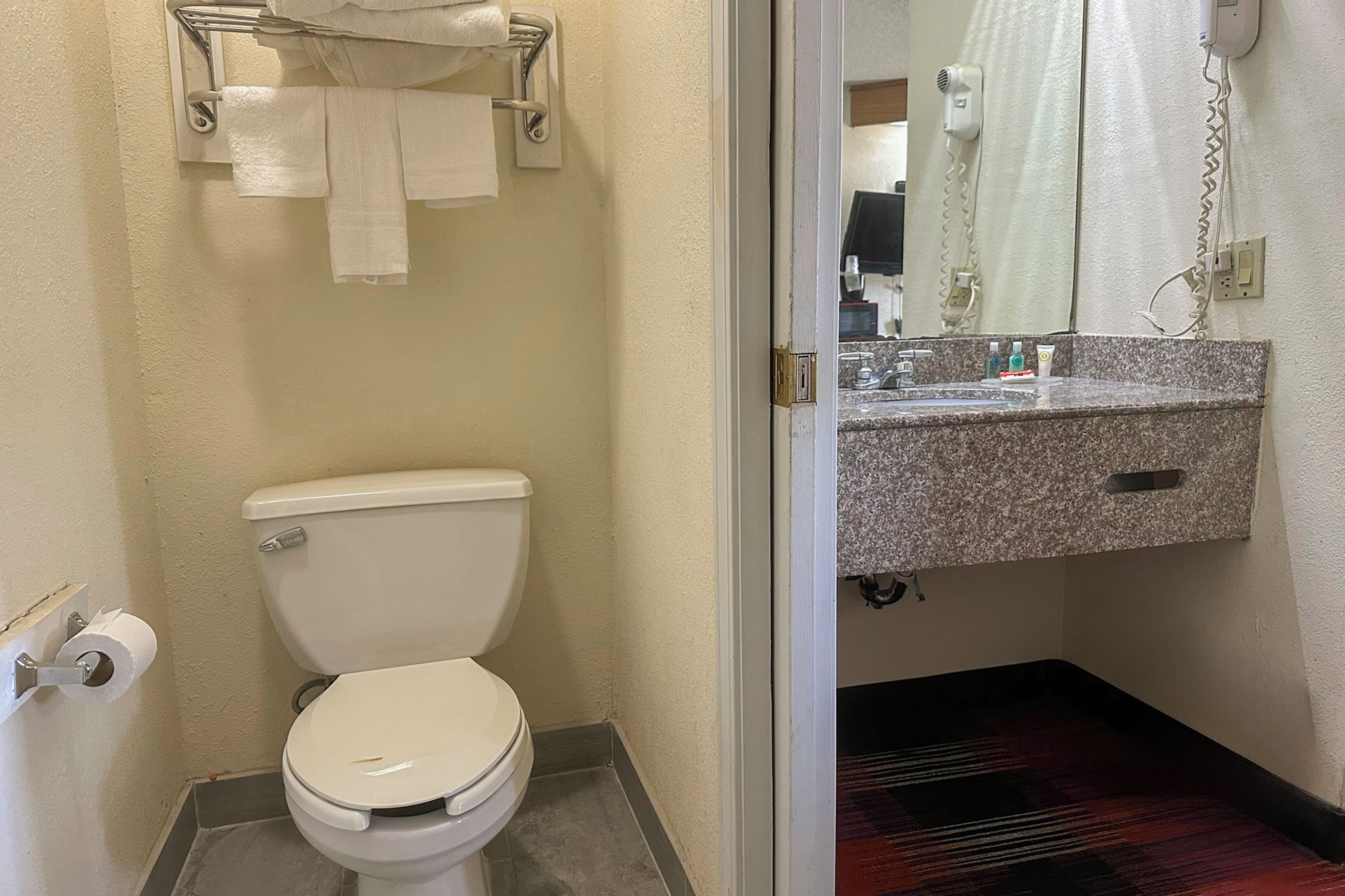 Un baño con inodoro, toallero, lavabo con artículos de aseo y zona de ducha.