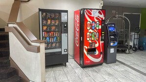 A vending machine and an ATM in a public area with a staircase and a cart. - Classic Inn By Townhouse American Way Memphis I 240 (Memphis)