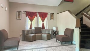 A living room with a sectional sofa, two armchairs, a small table, and a staircase. - Classic Inn By Townhouse American Way Memphis I 240 (Memphis)