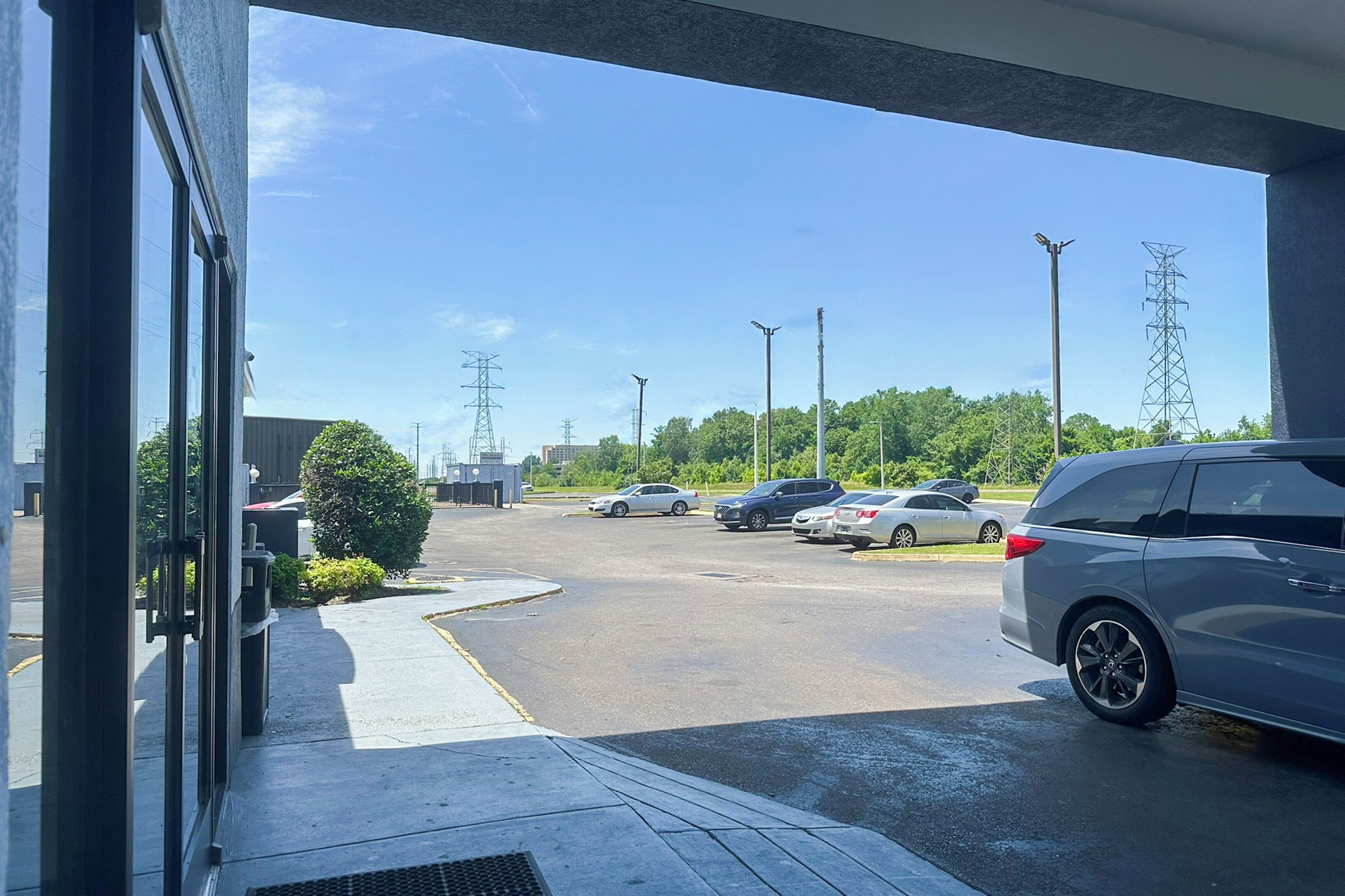 A parking lot with several cars, a building entrance, and a clear sky.