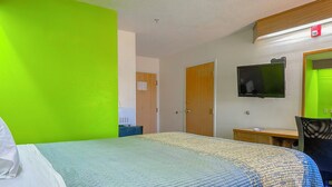 A hotel room with a bed, a television mounted on the wall, a desk, and a chair. - Classic Inn By Townhouse American Way Memphis I 240 (Memphis)