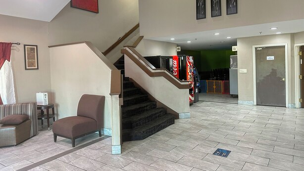 A hotel lobby with a staircase, seating area, and vending machines. - Classic Inn By Townhouse American Way Memphis I 240 (Memphis)