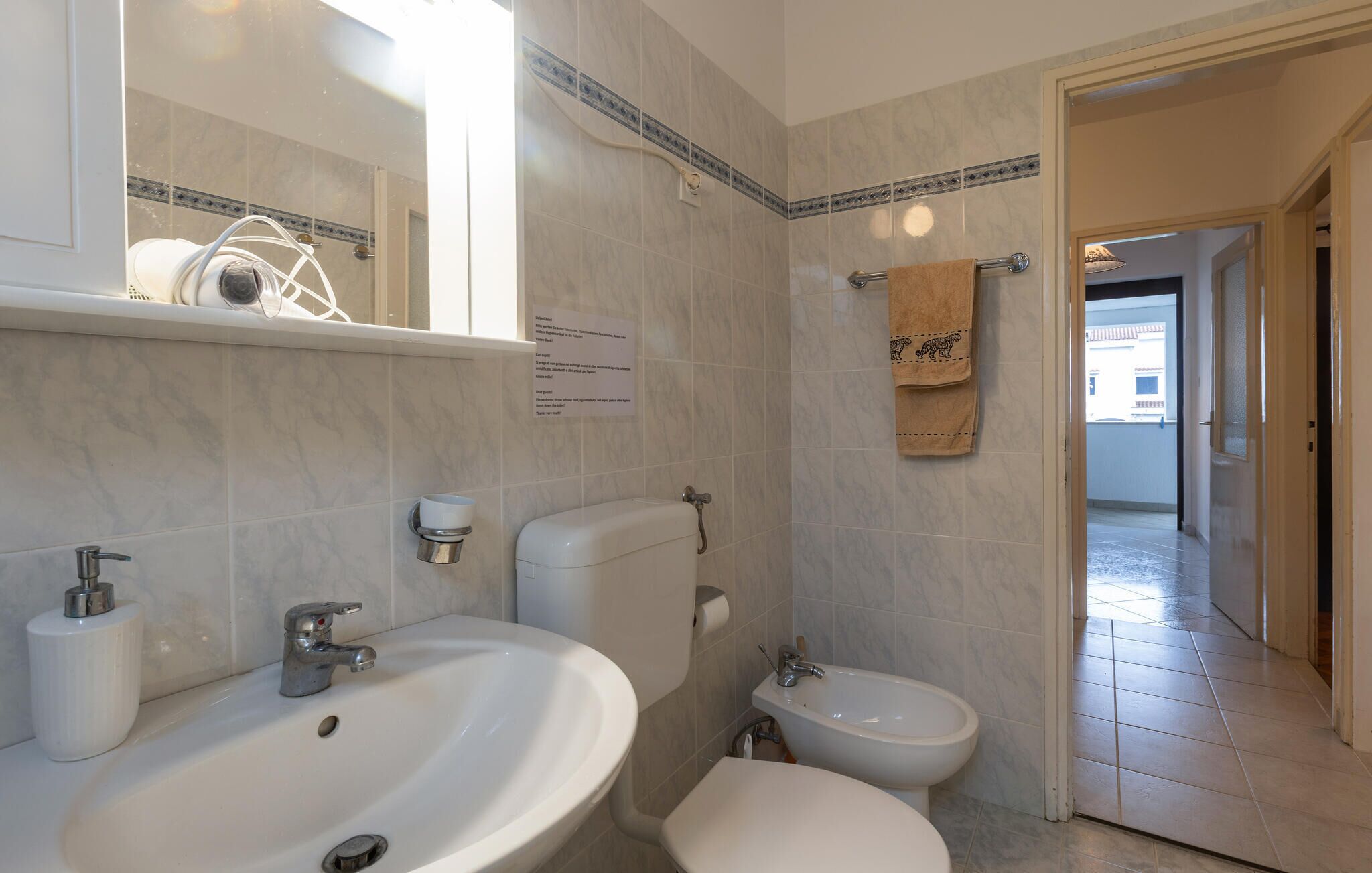 Ein Badezimmer mit Waschbecken, Toilette, Bidet und einem Handtuch an der Wand.