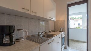 A modern kitchen with white cabinets, a stainless steel sink, and a coffee maker.