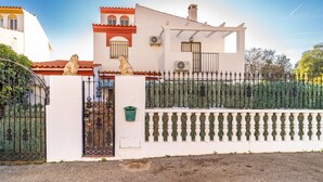 Una casa con fachada blanca, tejado rojo y estatuas decorativas de leones en la entrada.