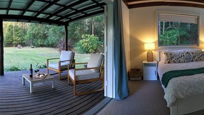 A bedroom with a bed, bedside tables, a window, and a view of a garden. - Kick back in a calm, stylish space in the foothills of the Watagan Mountains (Cooranbong)