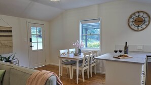 A modern kitchen with a dining area, wooden flooring, and a large window. - Kick back in a calm, stylish space in the foothills of the Watagan Mountains (Cooranbong)