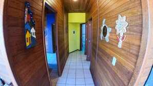 A hallway with wooden walls, a yellow accent wall, and a tiled floor. - Casa Vista Privilegiada - Piscina e Mar (Garopaba)
